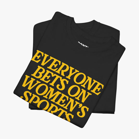 A folded black t-shirt with bold yellow text reading 'EVERYONE BETS ON WOMEN'S SPORTS' on a clean white background.