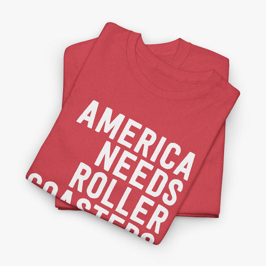 Two folded heather red t-shirts with white text reading America Needs Roller Coasters, stacked on a light gray background