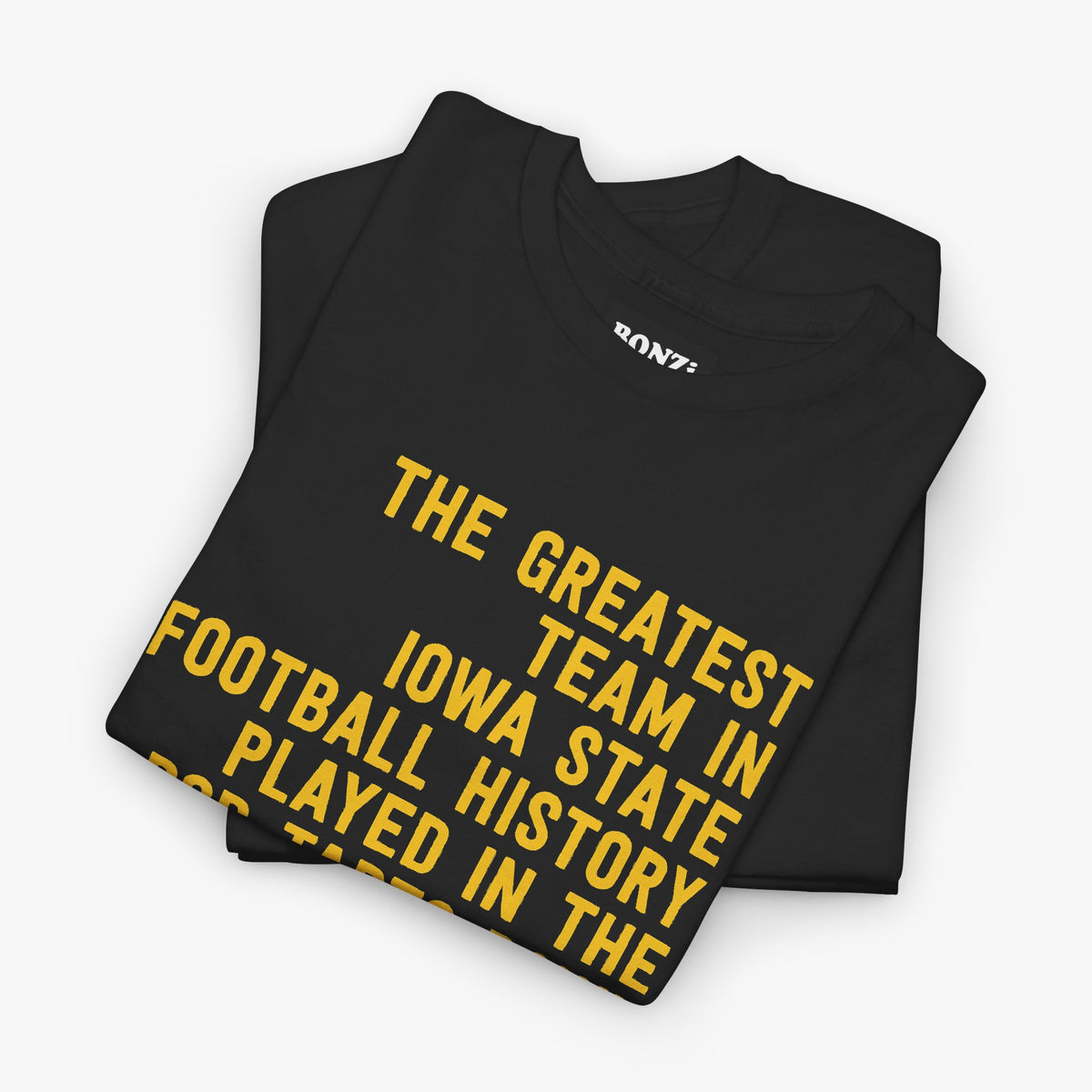Folded black t-shirt with gold text reading The Greatest Team In Iowa State Football History Played In The Pop-Tarts Bowl