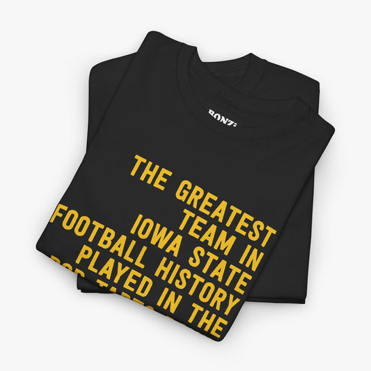 Folded black t-shirt with gold text reading The Greatest Team In Iowa State Football History Played In The Pop-Tarts Bowl