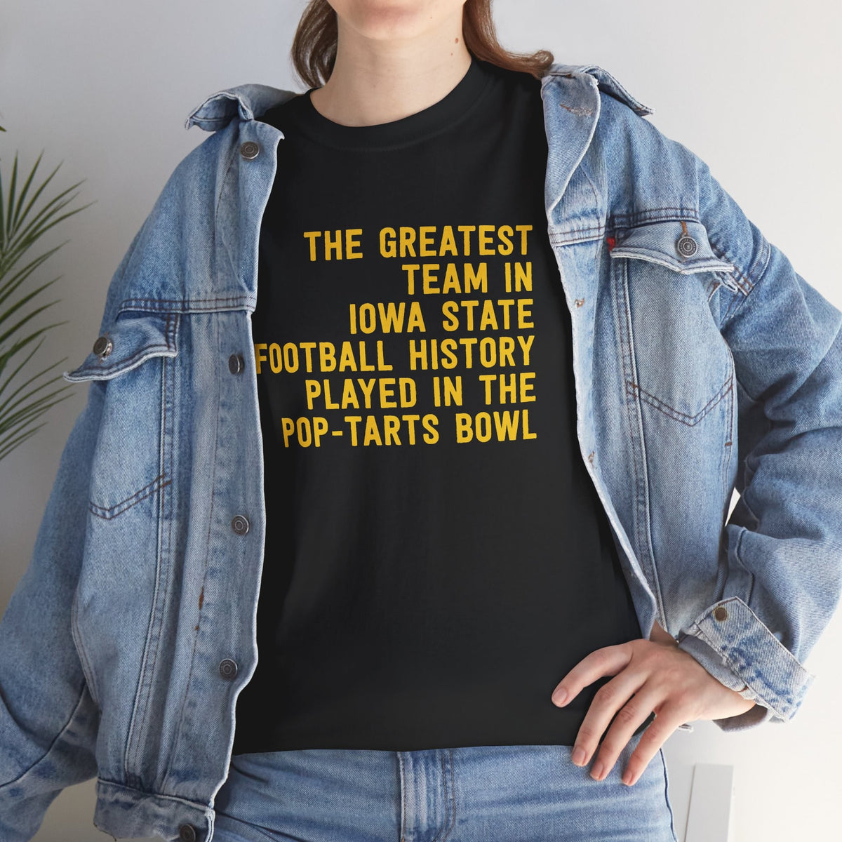 Woman wearing a black t-shirt with gold text reading The Greatest Team In Iowa State Football History Played In The Pop-Tarts Bowl