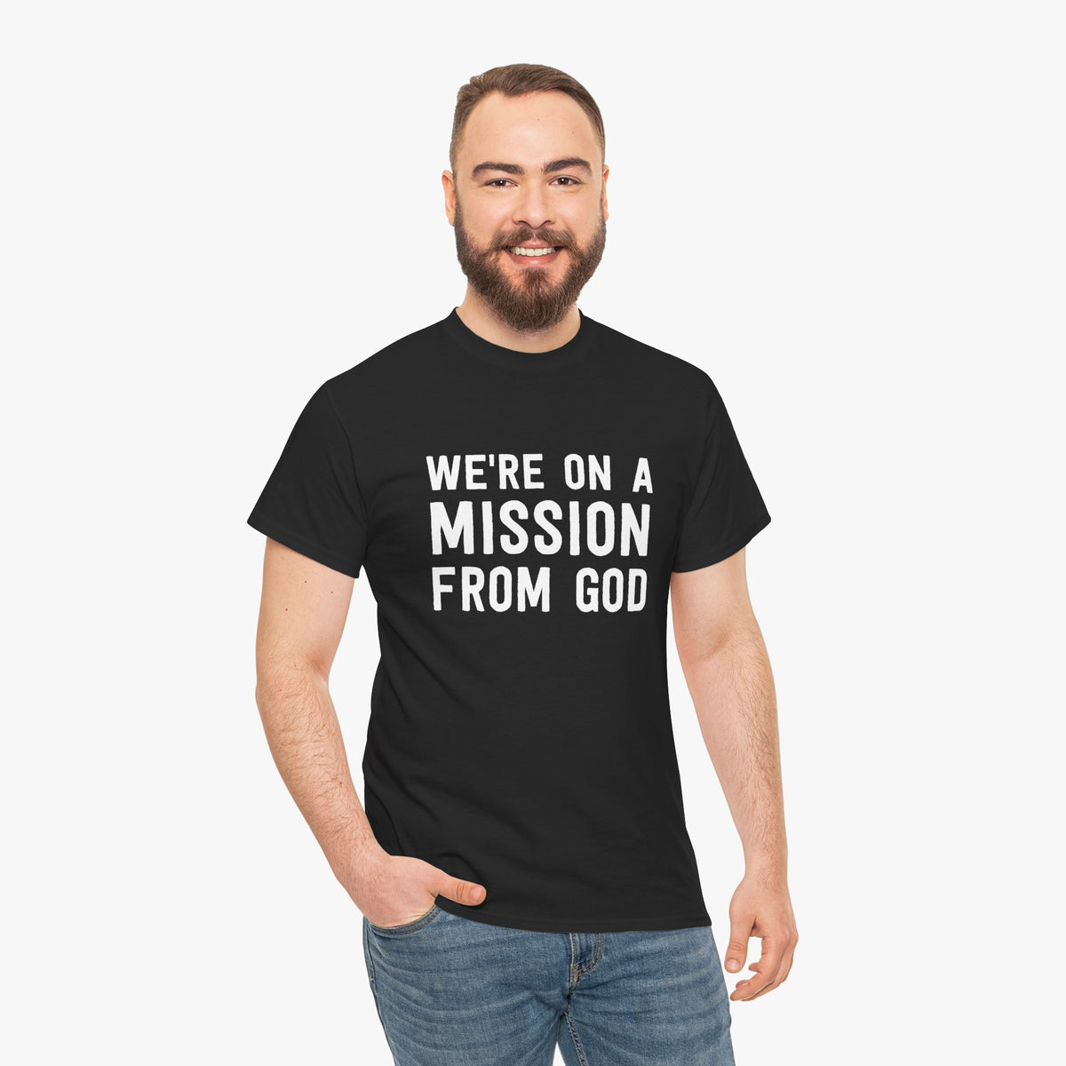 Smiling bearded man wearing a black t-shirt with white text reading We're On A Mission From God, paired with jeans
